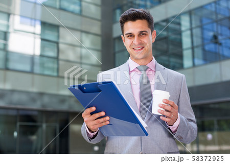 Smiling businessman reading papers Smiling businessman reading papers 58372925