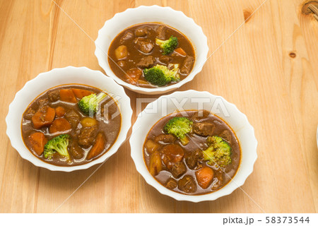木のテーブルの上の3皿のビーフシチュー 58373544