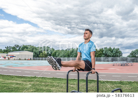 Male athlete lifting legs, exercise train muscles of abs abdomen, coach summer spring city, training Male athlete lifting legs, exercise train muscles of abs abdomen, coach summer spring city, training 58376613