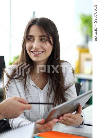Beautiful caucasian clerk showing something on tablet display Beautiful caucasian clerk showing something on tablet display 58376919