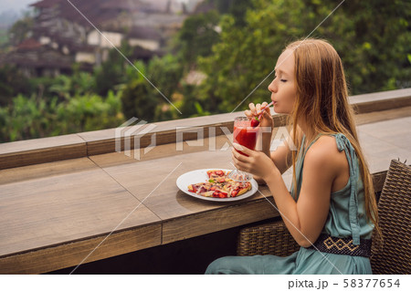 Woman eating delicious strawberry pizza on a balinese tropical nature background. Bali island Woman eating delicious strawberry pizza on a balinese tropical nature background. Bali island 58377654