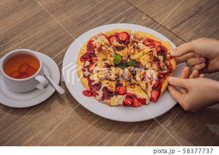 Woman eating delicious strawberry pizza on a balinese tropical nature background. Bali island Woman eating delicious strawberry pizza on a balinese tropical nature background. Bali island 58377737