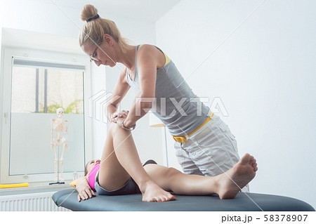 Physical therapist working on knee of woman 58378907