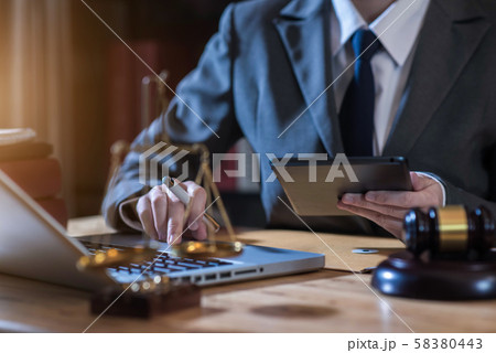 Justice and law concept.Male judge in a courtroom the gavel, working with digital tablet computer on wood table in sun light. Justice and law concept.Male judge in a courtroom the gavel, working with digital tablet computer on wood table in sun light. 58380443