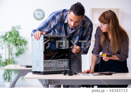 Two repairmen repairing desktop computer 58383713