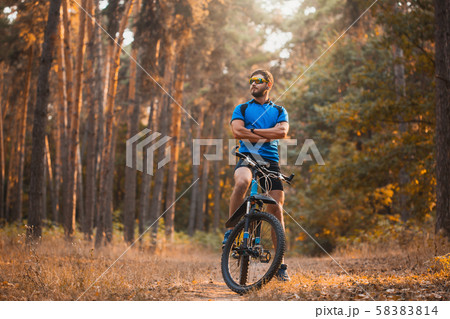 bearded man cyclist rides in the forest on a mountain bike. 58383814