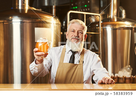 Bartender at bar conter holding beer glass with foam. 58383959