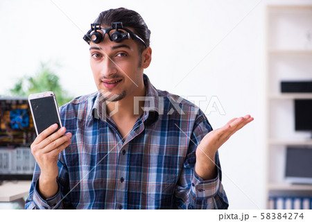 Young handsome technician repairing mobile phone Young handsome technician repairing mobile phone 58384274