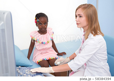 Afro girl sitting on bed, while ultrasound of knee join. Afro girl sitting on bed, while ultrasound of knee join. 58384394