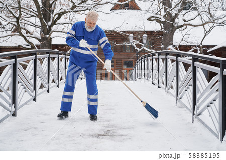 Man standing on bridge and removing snow in winter Man standing on bridge and removing snow in winter 58385195