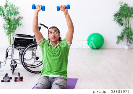 Young man in wheel-chair doing exercises indoors Young man in wheel-chair doing exercises indoors 58385975