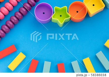 Frame from kids toys, top view on children's educational games on blue paper background. Multicolored wooden bricks, abacus, circles, stars. Flat lay, copy space for text. 58386038