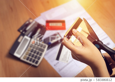 women use scissors to cut credit cards in hand with many credit card and statement on table for background women use scissors to cut credit cards in hand with many credit card and statement on table for background 58386812