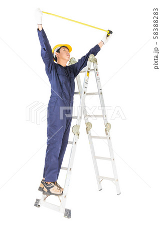 Handyman in uniform standing on ladder while using Handyman in uniform standing on ladder while using 58388283