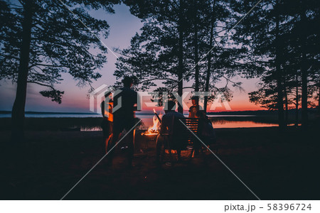 Group of young happy friends sitting by the fire at summer beach 58396724