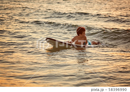Boy floats on surf board. Beginner surfer, first lessons Boy floats on surf board. Beginner surfer, first lessons 58396990