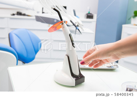 A doctor's hand holding a polymerization UV lamp. A doctor's hand holding a polymerization UV lamp. 58400345