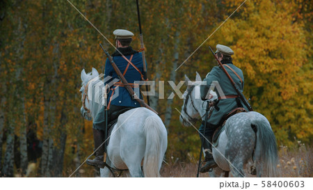 A reconstruction of military operations in Russia in 1917 - Two military men riding horses into the A reconstruction of military operations in Russia in 1917 - Two military men riding horses into the 58400603