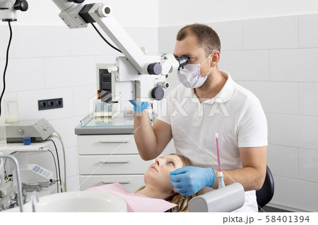Medical dentist in dental office talking with female patient and preparing for treatment. 58401394