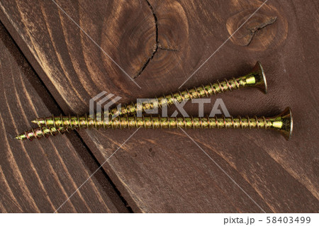 Glossy metallic bolt on brown wood Glossy metallic bolt on brown wood 58403499