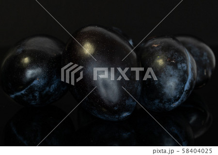 Fresh purple plum isolated on black glass Fresh purple plum isolated on black glass 58404025