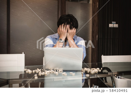Asian depressed businessman with casual suit in seriuos action while working with computer laptop and take medicine in modern meeting room office, Business lifestyle and depress concept Asian depressed businessman with casual suit in seriuos action while working with computer laptop and take medicine in modern meeting room office, Business lifestyle and depress concept 58410491