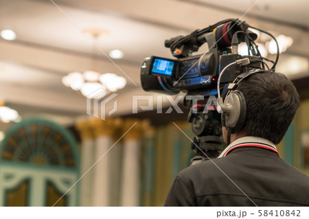 Rear side of Video Cameraman taking photograph to Asian Speaker with casual suit on the stage present the screen in the conference hall or seminar meeting, event and seminar production concept Rear side of Video Cameraman taking photograph to Asian Speaker with casual suit on the stage present the screen in the conference hall or seminar meeting, event and seminar production concept 58410842