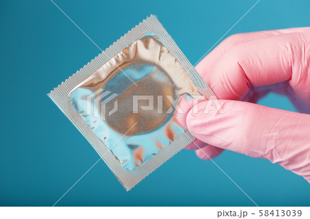 Condom contraception A hand in a pink glove holds 58413039