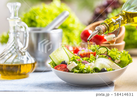 Olive oil pouring in to the fresh vegetable salad. 58414631