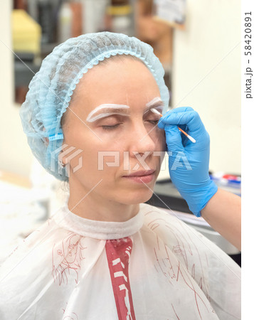Coloring eyebrows with henna in the beauty salon. 58420891