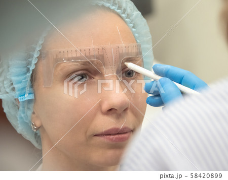 Coloring eyebrows with henna in the beauty salon. 58420899