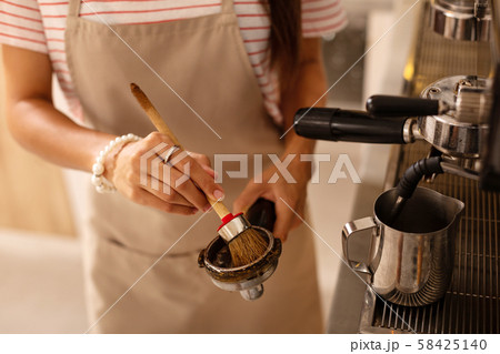 Barista using special brush while cleaning parts of coffee machine Barista using special brush while cleaning parts of coffee machine 58425140