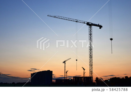 Jib construction tower cranes at a construction site on the sunset and blue sky background Jib construction tower cranes at a construction site on the sunset and blue sky background 58425788