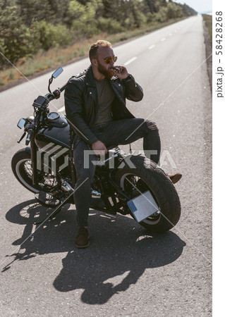 Sexy brutal biker posing on the bike backwards smoking sigar 58428268
