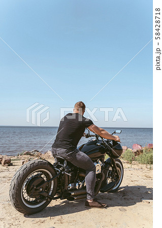 Back view of an athletic biker sitting on bike looking at the ocean Back view of an athletic biker sitting on bike looking at the ocean 58428718