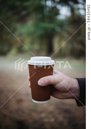 A man holds a takeaway cardboard glass with tea A man holds a takeaway cardboard glass with tea 58430492