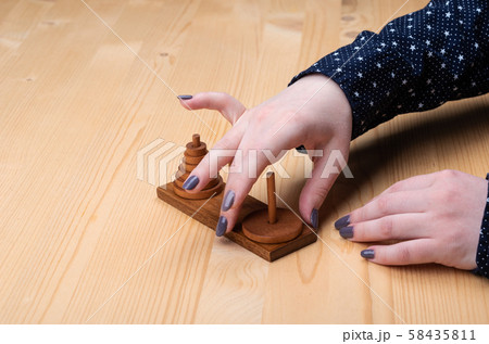 Girl plays puzzle tower of hanoi. Dark manicure. Girl plays puzzle tower of hanoi. Dark manicure. 58435811