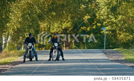 Two bikers on their bikes are standing on the road Two bikers on their bikes are standing on the road 58435871