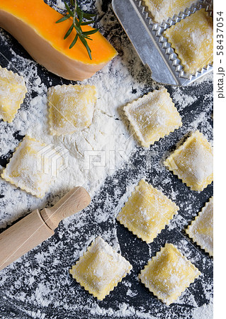 traditional raw ravioli with pumpkin on a wooden table with flour, handmade, cooking process 58437054