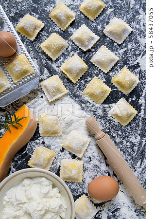 traditional raw ravioli with pumpkin on a wooden table with flour, handmade, cooking process 58437055