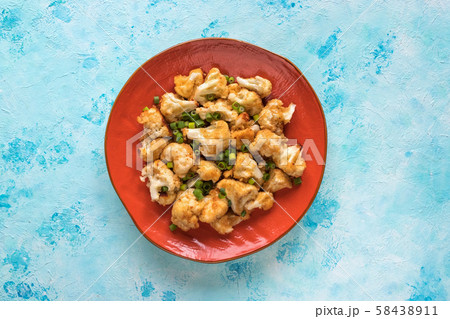 Pieces of fried cauliflower on an orange plate.  58438911