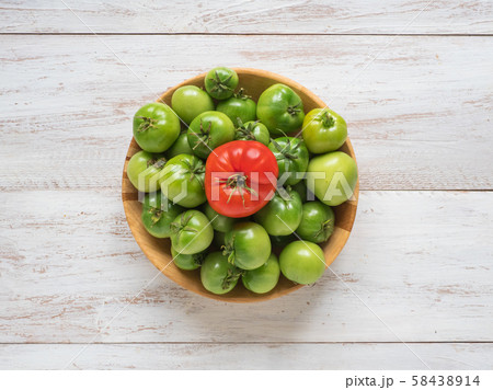 One red tomato among several green tomatoes  58438914
