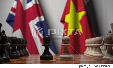 Flags of the United Kingdom and Vietnam behind pawns on the chessboard. Chess game or political 58439969