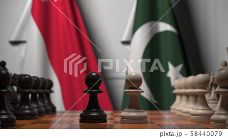 Flags of Singapore and Pakistan behind pawns on the chessboard. Chess game or political rivalry 58440079