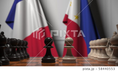 Flags of France and Philippines behind pawns on the chessboard. Chess game or political rivalry Flags of France and Philippines behind pawns on the chessboard. Chess game or political rivalry 58440553