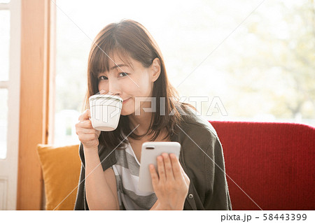 カフェでコーヒーを飲みながらスマホを見る女性 カフェでコーヒーを飲みながらスマホを見る女性 58443399