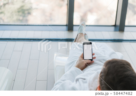 Relax in the hotel with a phone in hand. A man lying on a lounger by the pool and enjoying 58447482