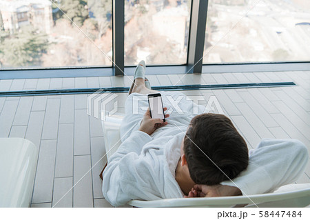 Relax in the hotel with a phone in hand. A man lying on a lounger by the pool and enjoying 58447484