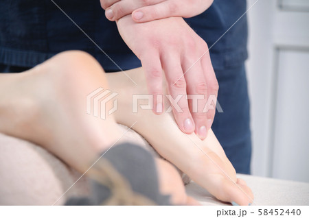 Close-up Relaxing foot massage at the spa. Male hands knead the female foot. Body care concept 58452440