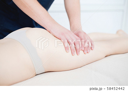 Closeup of the arm of a masseur male doing hip massage to a girl in a spa salon. Massage and body 58452442
